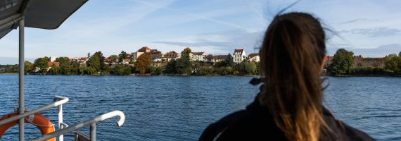 Eine Person schaut von der Fähre auf das Wasser