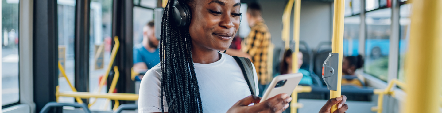 Frau in Tram schaut auf Handy und grinst